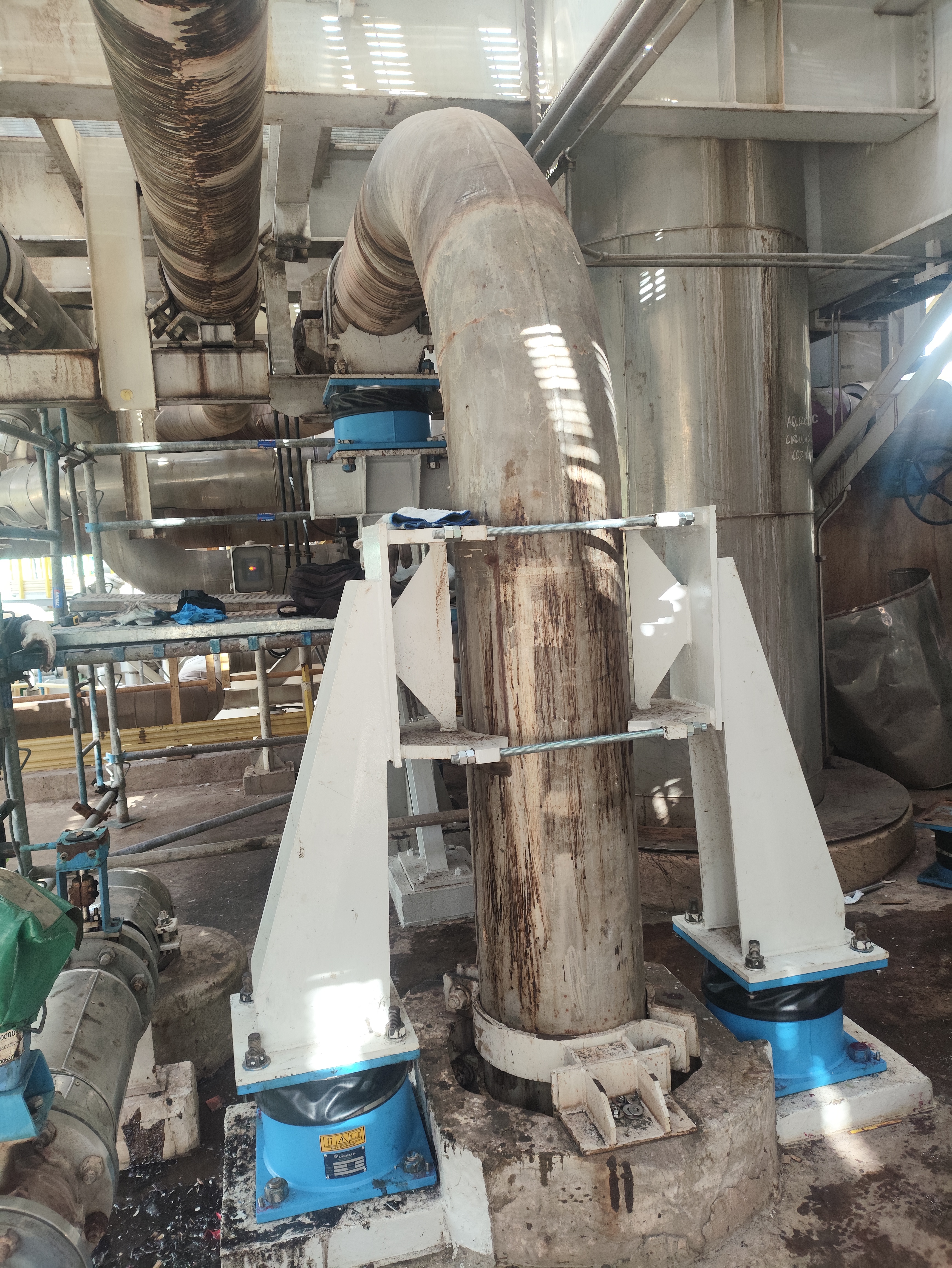 Estrutura de suporte com isoladores de mola azuis instalada em coluna industrial de grande diâmetro em planta de processo